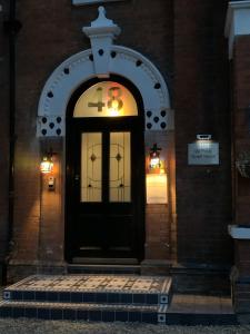 uma porta preta da frente de um edifício à noite em De Parys Guest House - Fully Airconditioned em Bedford