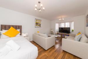 a bedroom with a bed and a couch and a tv at Greenfield's Oxlade Home - Modern 3 Bed room House, Langley, Slough in Slough