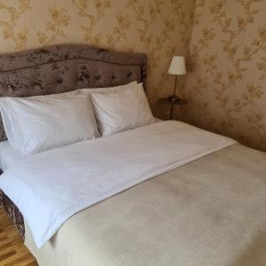 uma cama com lençóis brancos e almofadas num quarto em Rietumkrasta seaside apartment em Liepāja