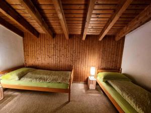 a bedroom with two beds and a wooden ceiling at Half chalet with garden & balcony - 4' to the lake in Laax