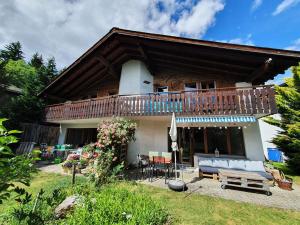 a house with a balcony and a table and chairs at Half chalet with garden & balcony - 4' to the lake in Laax