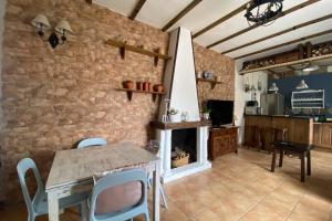 cocina con mesa, sillas y chimenea en La Casona del Molino en el bosque en El Bosque