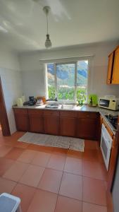 a kitchen with a sink and a large window at Apartamento Vai Vem in Madalena do Mar