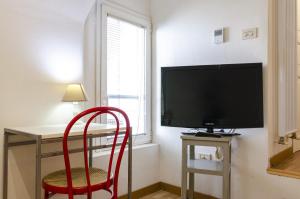 een kamer met een bureau, een televisie en een rode stoel bij Appartamento piccolo nel cuore della citta' by Wonderful Italy in Bologna
