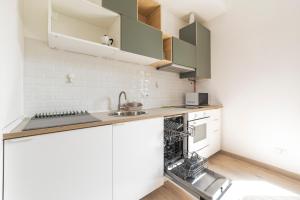 a kitchen with white cabinets and a sink at Maciachini Renovated Studio! in Milan