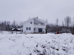 a white house in a snow covered field at Lakeview lodge Tree of Life, Skagern Lake in Finnerödja