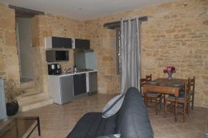 uma sala de estar com um sofá, uma mesa e uma cozinha em Gite de Charme em Calviac