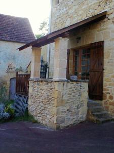 kamienny dom z drewnianymi drzwiami i werandą w obiekcie Gite de Charme w mieście Calviac