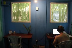 a man sitting at a desk with a laptop computer at Lagarto Na Banana Hostel in Pipa