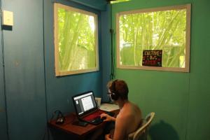 a man sitting at a desk with a laptop computer at Lagarto Na Banana Hostel in Pipa