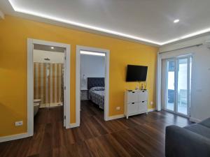 een slaapkamer met gele muren en een bed en een televisie bij Sorrento Punto It Apartment in Sorrento