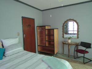 een slaapkamer met een bed, een tafel en een spiegel bij Serendipity NO TV in Polokwane
