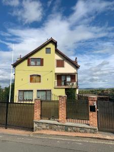 een geel huis met een hek ervoor bij Casa din Deal in Sibiu