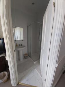 a white bathroom with a shower and a sink at The Fieldings in Truro