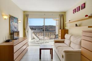 een woonkamer met een bank en uitzicht op een balkon bij Sea View Apartment en Mogán in Playa del Cura