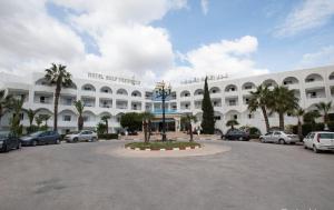 a large white building with cars parked in a parking lot at Hotel Golf Residence in Hammam Sousse