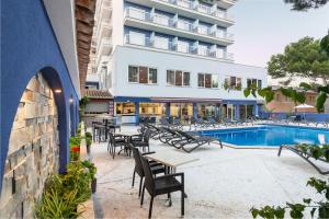 un patio del hotel con mesas y sillas junto a una piscina en Hotel Torre Azul & Spa - Adults Only, en El Arenal