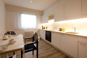 a kitchen with white cabinets and a table and a sink at City Flair in Seenähe in Bregenz