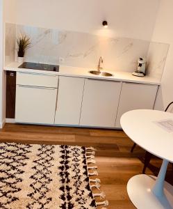 a kitchen with white cabinets and a sink and a table at Gästehaus zur Uni Klinik Exklusives Apartment mit Küche und Badezimmer in Homburg