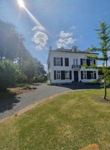 a large white house sitting on top of a yard at Chambres d'Hôtes des Rouets in Fourmies