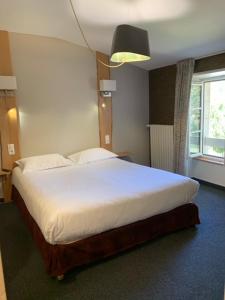 a bedroom with a large white bed with a window at Logis Auberge De La Riviere in Velluire