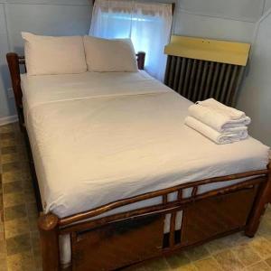 ein Bett mit weißer Bettwäsche und Handtüchern darauf in der Unterkunft Historic Wigwam Village No 2 in Cave City