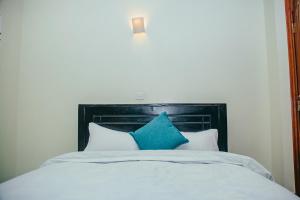 1 cama con cabecero negro y almohadas azules en Elegant Art Deco Home with Free Wi-Fi, Parking, Netflix, Office Desk, Computer & Baby Cot in Ruaka en Ruaka