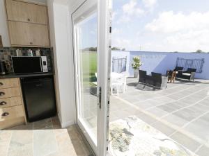 a kitchen with a sliding glass door leading to a patio at Drws y Gorlan in Llanerchymedd