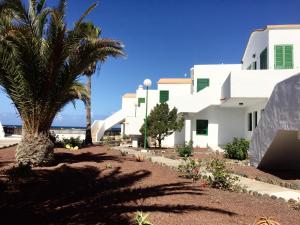 a white building with palm trees in front of it at Apartamento Los Lagos Renovated New Kitchen & More in El Cotillo