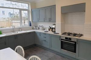 eine Küche mit blauen Schränken, einer Spüle und einem Herd in der Unterkunft Beautiful house next to Beach & Park nr Zoo Newly refurbished in Kent