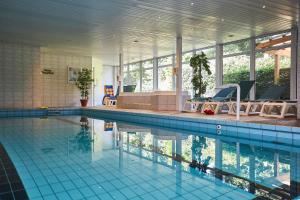 a large swimming pool with chairs and a swimming pool at Flairhotel Hubertus in Bad Zwischenahn