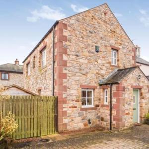 a brick house with a wooden fence in front of it at Stunning Lake District Cottage in Penrith