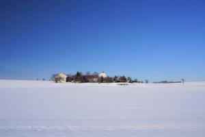 un campo cubierto de nieve con casas en el fondo en Gutshof Dobschütz - Urlaub auf dem Bauernhof, en Nossen