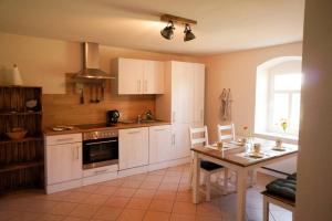 a kitchen with white cabinets and a table and a window at Gutshof Dobschütz - Urlaub auf dem Bauernhof in Nossen