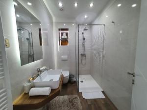 ein weißes Bad mit einem Waschbecken und einer Dusche in der Unterkunft Beach Apartments Maris in Rogoznica