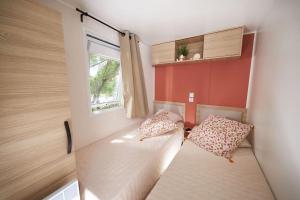 レ・マトゥにあるMobil home 3 chambres 2 salles de bains au camping 4 étoiles MH276 aux charmettesのベッドと窓が備わる小さな客室です。