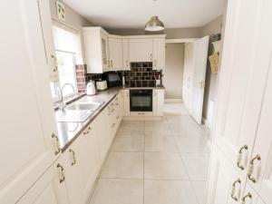 a kitchen with white cabinets and a sink at Curragh Hill in Westport