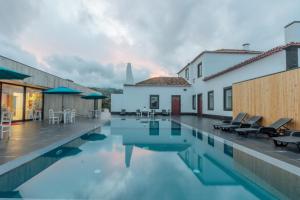 a villa with a swimming pool and a house at Solar Do Conde Garden Hotel in Capelas