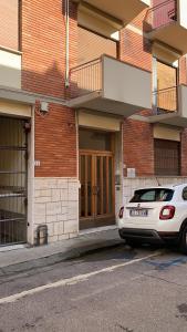 una macchina bianca parcheggiata di fronte a un edificio di mattoni di Pampero & Catona House a Pisa
