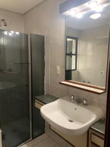 La salle de bains est pourvue d'un lavabo et d'une douche. dans l'établissement Flat Belvedere com piscina, à São Vicente