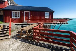 a red building on a dock with the water at Å-Hamna Rorbuer in Å