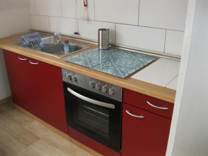 a kitchen with red cabinets and a stove and a sink at Ferienwohnung ULLABRU in Ascheffel