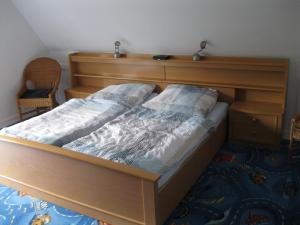 ein Holzbett mit einem Kopfteil aus Holz im Schlafzimmer in der Unterkunft Ferienwohnung ULLABRU in Ascheffel