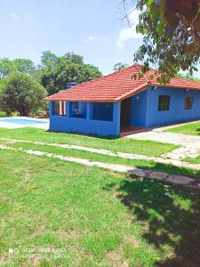 a blue house with a red roof and a yard at Chácara Nilton soares in São José da Barra
