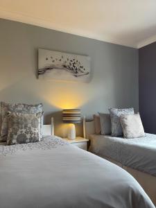 a bedroom with two beds and a lamp at Greenfields Country House in Latton