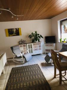 ein Wohnzimmer mit Fernseher und Tisch und Stühlen in der Unterkunft Luftkurort, Perle des Neckartals in Hirschhorn