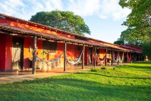 a red building with hammocks in front of it at SouthWild Pantanal Lodge in Pixaim