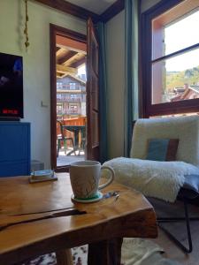 - une tasse de café sur une table en bois dans le salon dans l'établissement appartement de standing Arc 1950, à Bourg-Saint-Maurice