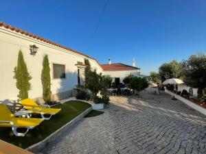 a house with a patio with yellow chairs and a yard at Casa Santo António in São Brás de Alportel