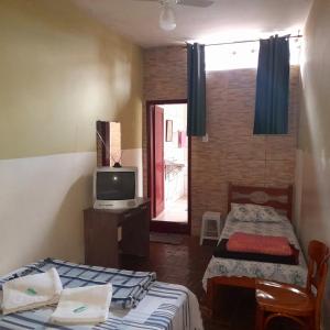 a small room with two beds and a television at Hotel Shangri-la in Três Corações